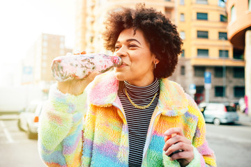 Young beautiful multiethnic woman outdoors drinking from reusable bottle