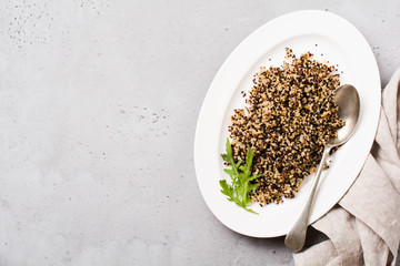 Quinoa for wholesome meal served in simple ceramic plate on old dark background. Top view.