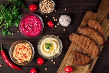 Traditional Middle eastern chickpea hummus, carrot hummus, beetroot hummus with crispy bread	