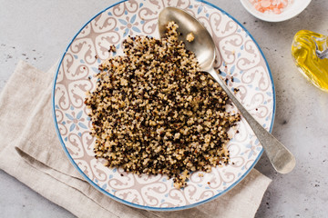 Quinoa for wholesome meal served in simple ceramic plate on old dark background. Top view.