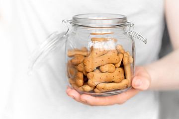 man holds dog cookies in the jar on a light background