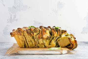 Pull-apart bread with Italian pasta pesto, basil and parmesan cheese in baking form over old light...