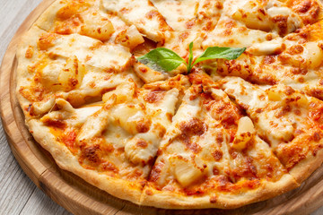 Tasty hawaiian pizza with chicken and pineapple on wooden cutting board