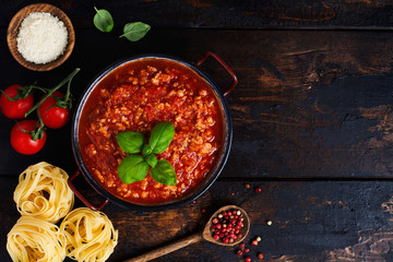 Traditional italian Bolognese sauce in saucepot an old dark wooden background. Top view, copy space