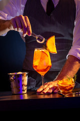 Bartender adding ice cubes into Aperol spritz cocktail
