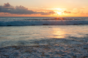 The sun illuminates the shore and the waves at sunset