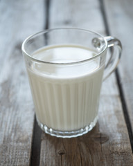Glass mug with milk on an unpainted wooden table