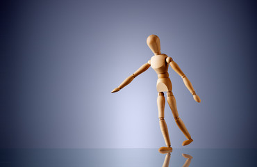 eine Holzfigur balanciert auf einer Mauer