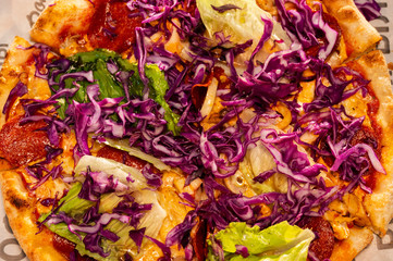 Close-up of thin pizza with fresh vegetables and herbs. tasty fresh pizza with cabbage and lettuce. fast food