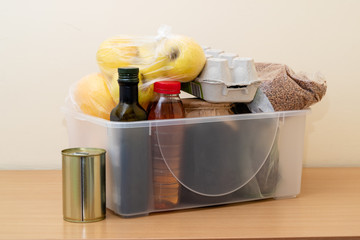 Plastic box with a set of food: eggs, buckwheat, apples, oranges, fruits, oil, canned food.