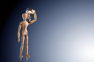 eine Holzfigur hält ein Glühbirne