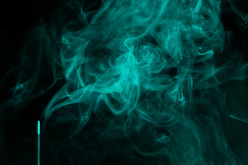 incense smoke. smoldering piece of wood . incense sticks in blue lighting. aromatic smoke . Green colour.