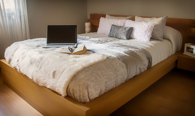 Cozy bedroom of a house. Laptop and book on the bed. Decor