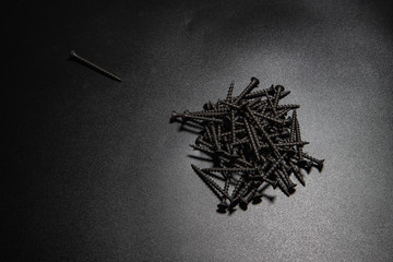 black wood screws on a black table. Construction, repair, installation and fixing