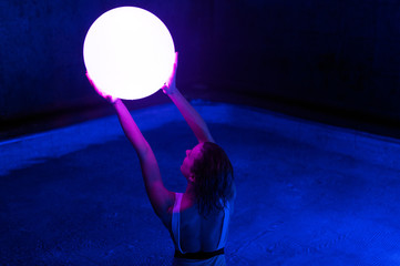 Relaxed young woman in pool with neon light