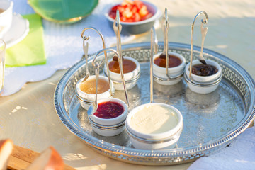 Homemade french brioche breakfast on a cutting board with homemade jam and butter in cups. Sunny day in summer. Relaxing, good feeling. Tasting different types of jam. Green details