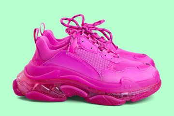 Pair of new trendy fuchsia sneakers isolated on a light green background with shadow. Side view.