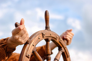 Steering hand wheel ship on sky background, hand hold hand wheel