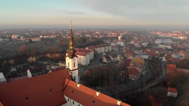 Winter sunrise glinting off the golden steeple cross on The Church of St. Phillip and James, Vukovar Croatia, aerial