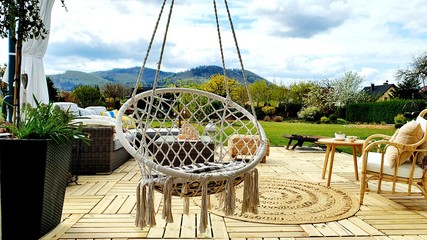  A relaxing spot for a warm, summer day - a stylish, wooden terrace with wicker garden furniture,...