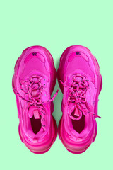 Pair of new trendy fuchsia sneakers isolated on a light green background with shadow. Top view.