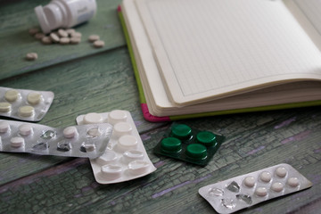 Medical concept. Pills, notebook on green wooden background