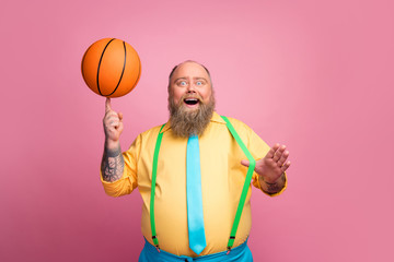 Portrait of his he nice cheerful cheery bearded guy spinning orange ball on finger having fun...
