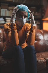 Obraz premium Woman with protective antiviral mask sitting at home in isolation / quarantine.
