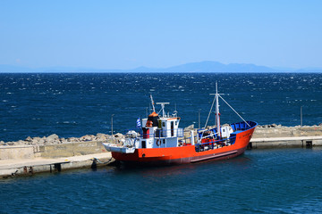 Fototapeta premium red fishing boat in Kamariotissa harbor (Samothraki) - view taken from ferry