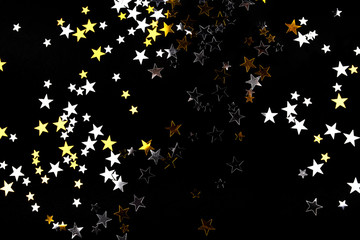 Golden and silver stars on black background. Flat lay, top view.
