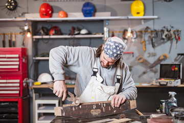 Male carpenter working on old wood in a retro vintage workshop.