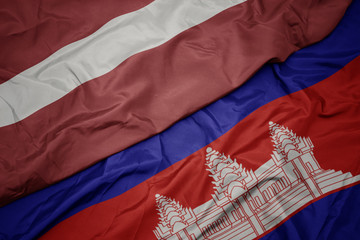 waving colorful flag of cambodia and national flag of latvia.