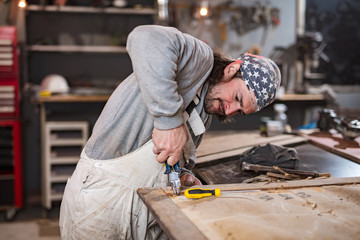 Male carpenter working on old wood in a retro vintage workshop.