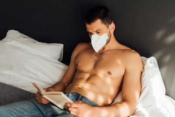 sunlight on shirtless man in medical mask reading book in bed