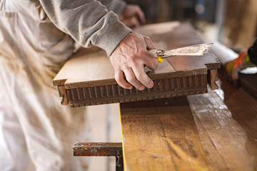 Male carpenter working on old wood in a retro vintage workshop.