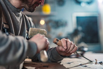 Male carpenter working on old wood in a retro vintage workshop.