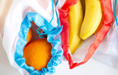 Zero waste, plastic recycled textile produce bag for carrying fruit (orange and a banana) or vegetables, a white surface.top view