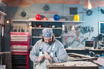 Male carpenter working on old wood in a retro vintage workshop.