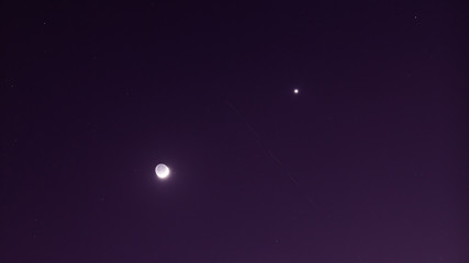 Young Moon and Venus on a dark night sky with satellite trails that can be seen these nights on a dark sky.