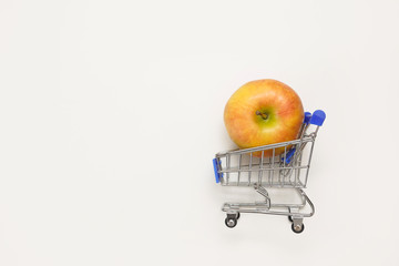 shopping trolley with apple on white background with copy space