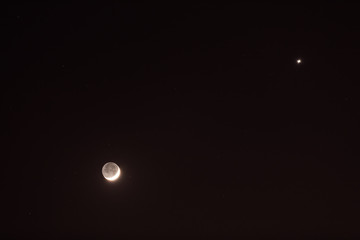 Young Moon and Venus on a dark night sky.