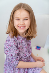 Naklejka premium Portrait little girl blonde in a purple dress.