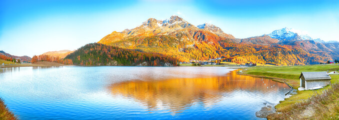Awesome autumn panorama of Silvaplana lake and Surlej village.