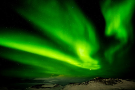 Green Aurora borealis streamers, northern Iceland with snow covered psuedo craters on the shores of Lake Myvatn