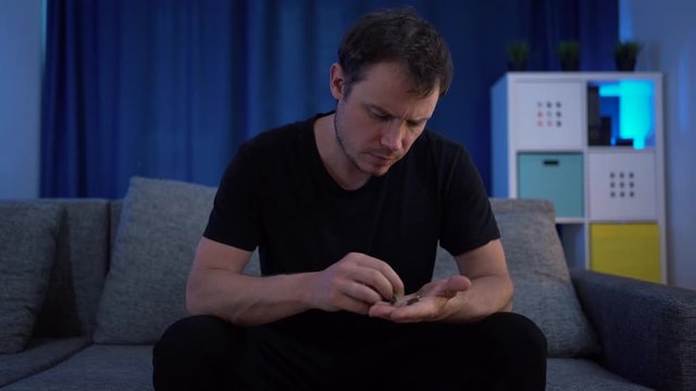 a man sitting counting money on the sofa, very few of them