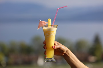 Pineapple cocktail in a woman hand with bokeh