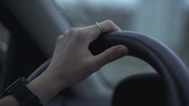 Plano detalle de la mano de una mujer conduciendo un coche. Lleva un anillo en la mano. C&aacute;mara lenta.