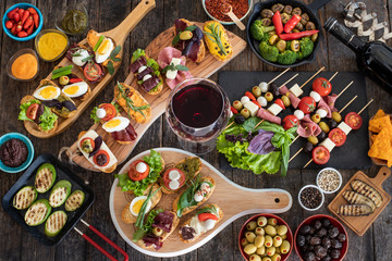 Many tapas on the rustic wooden table with black background