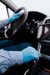 unrecognizable man driving a car wearing protective mask and gloves during pandemic coronacirus covid-19