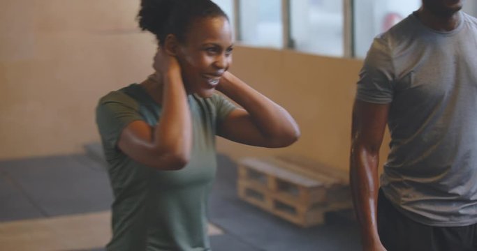 Laughing young African American woman in
sportswear talking with friends working out
together in a gym